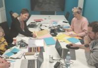 Neljä henkilöä askartele pöydän ääressä kartongista lappuja.