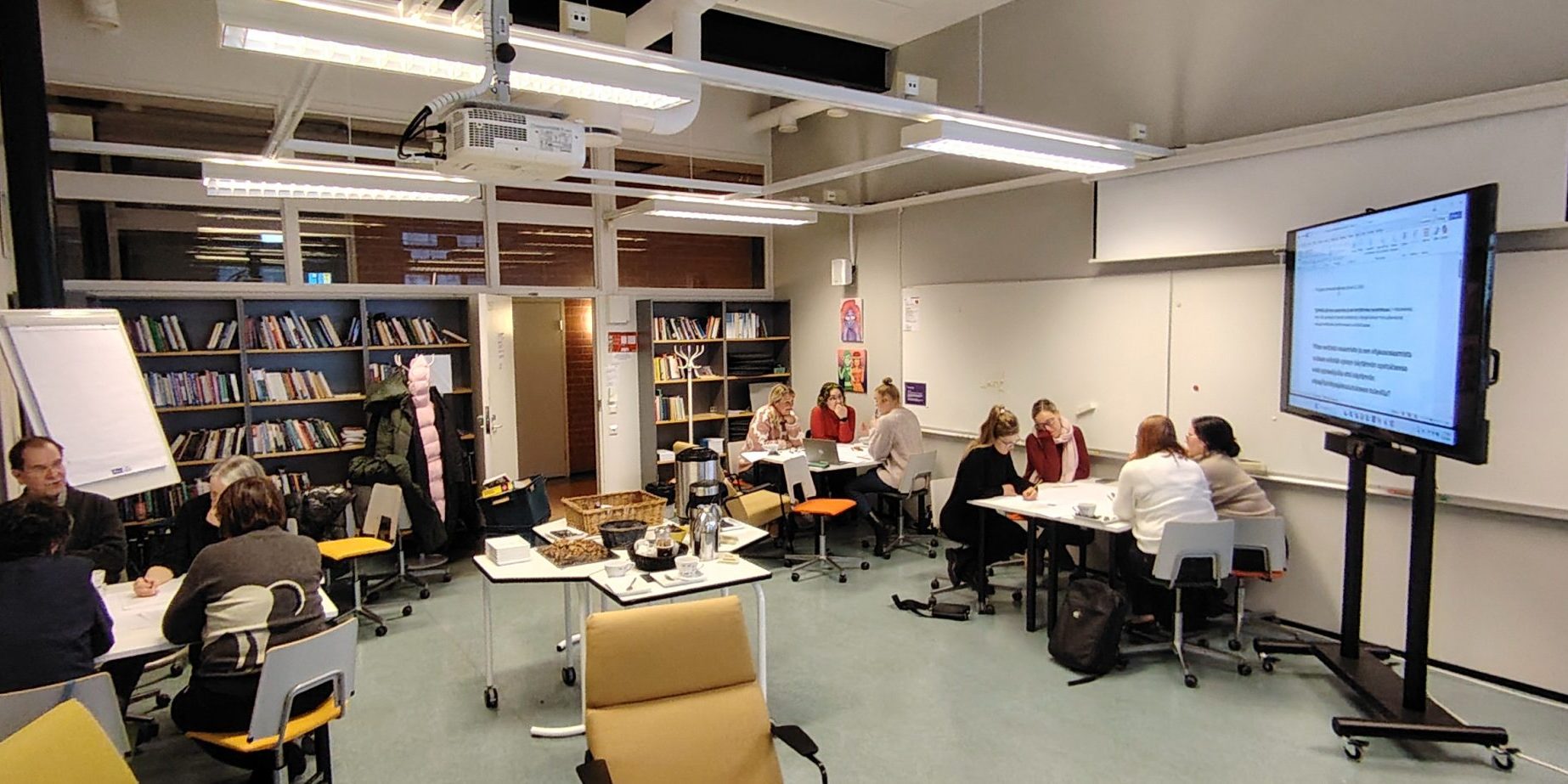 Yleiskuva luokkahuoneesta, jossa henkilöitä.